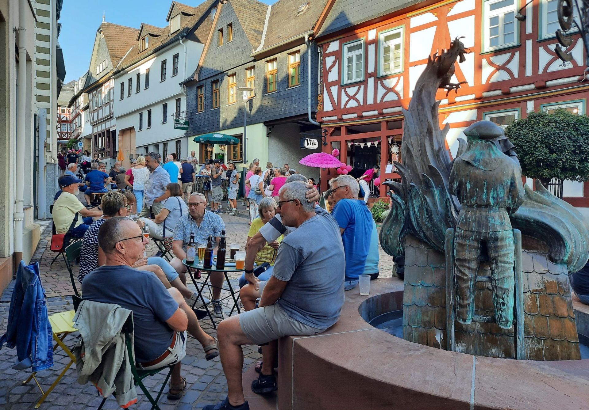 Zu sehen sind: Menschen beim gemütlichen Beisammensein - hier am Feuerwehrbrunnen in der historischen Altstadt.