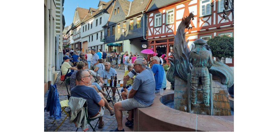 Zu sehen sind: Menschen beim gemütlichen Beisammensein - hier am Feuerwehrbrunnen in der historischen Altstadt.