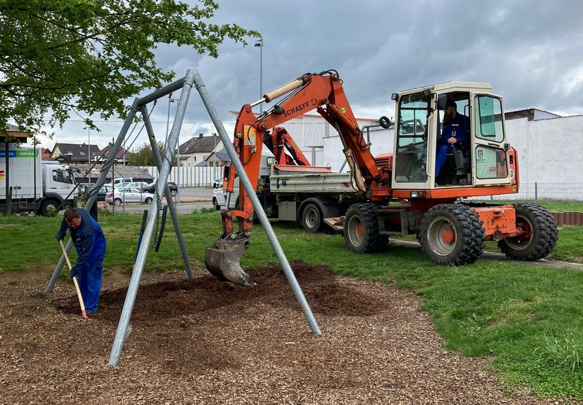 Mitarbeiter des Bauhofes erneuern den Fallschutz an einer Schaukel