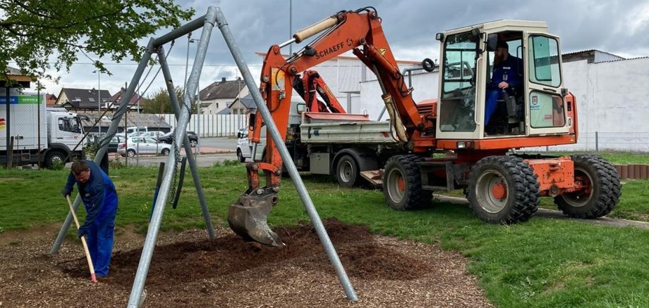 Mitarbeiter des Bauhofes erneuern den Fallschutz an einer Schaukel