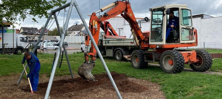 Mitarbeiter des Bauhofes erneuern den Fallschutz an einer Schaukel